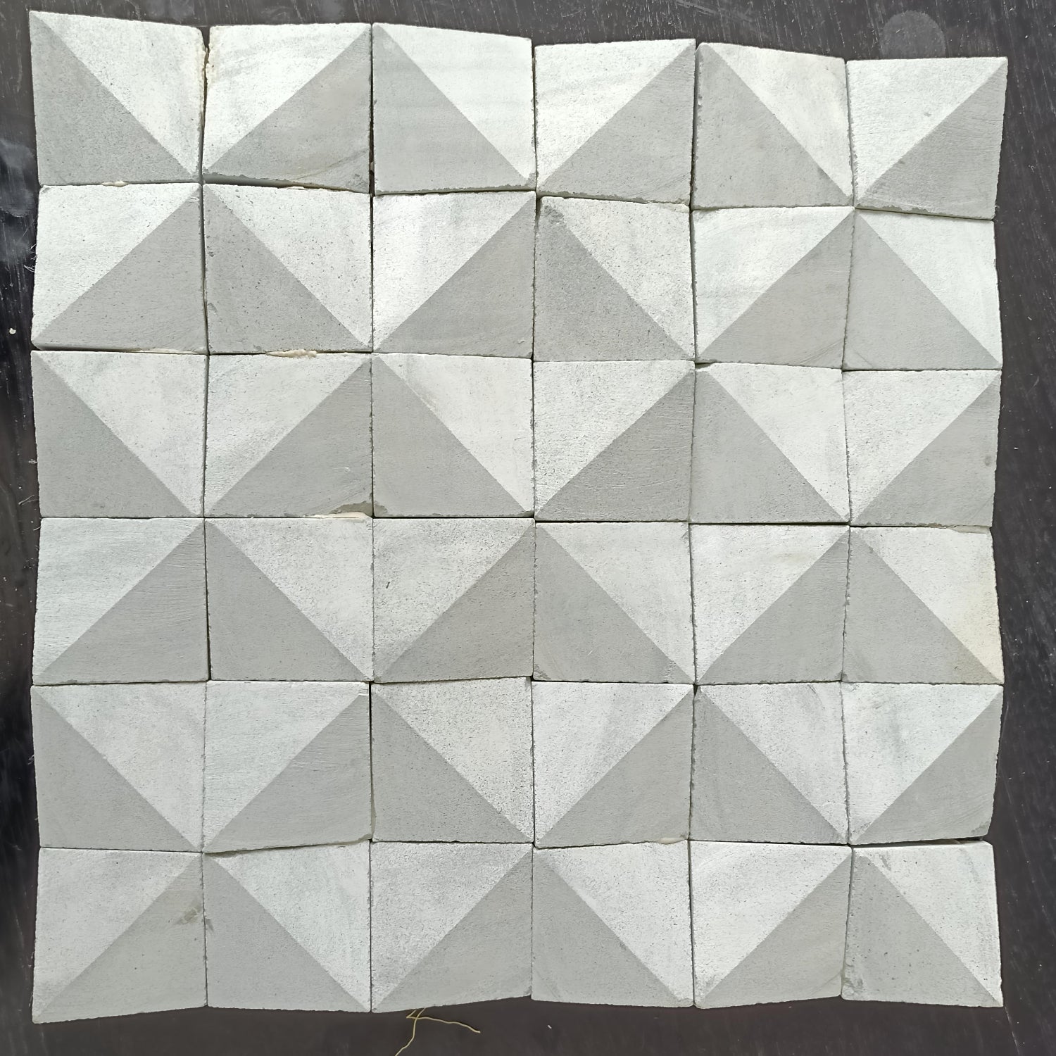 Geometric pattern of triangular concrete tiles on a dark surface